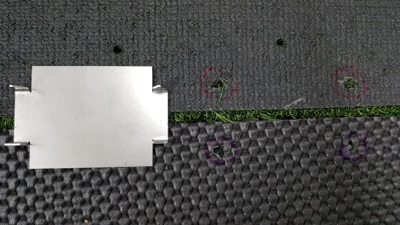 Klammer von oben mit markierten Löchern im TeeGras und der Hauptmatte